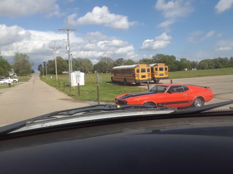 1994 Ford Bronco - Orange 1971 Ford Mustang Mach 1 parked on a road with two school buses in the background.