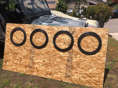 1992 Jeep Wrangler - Four wheel spacers are displayed on OSB plywood, with a Jeep Wrangler in the background.