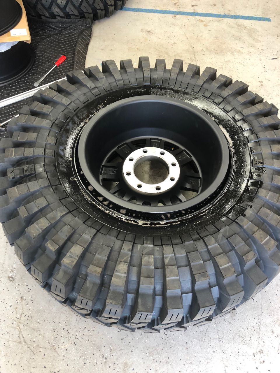 Off-road tire mounted on a black wheel with silver lug nuts
