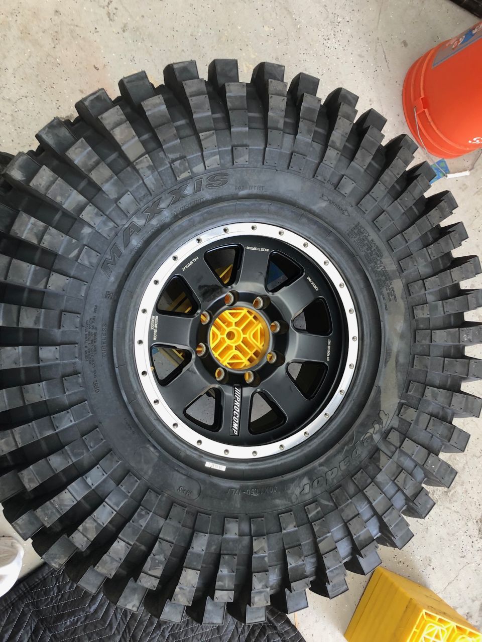 Maxxis off-road tire on a black wheel with yellow center cap