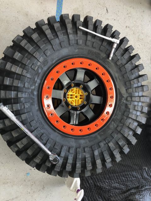 1992 Jeep Wrangler - A close-up view of a large off-road tire and wheel assembly, with tools present.