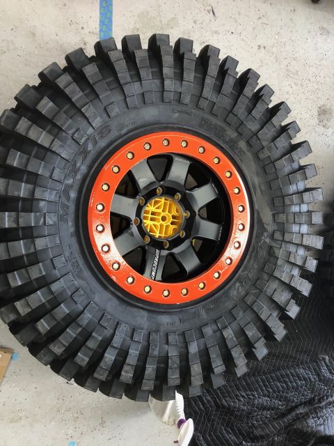 1992 Jeep Wrangler - This off-road tire features an aggressive tread pattern and is mounted on a black wheel with an orange beadlock ring.
