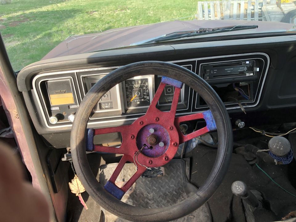 1978 Ford Bronco interior showing a custom red and purple steering wheel, dashboard gauges, and radio