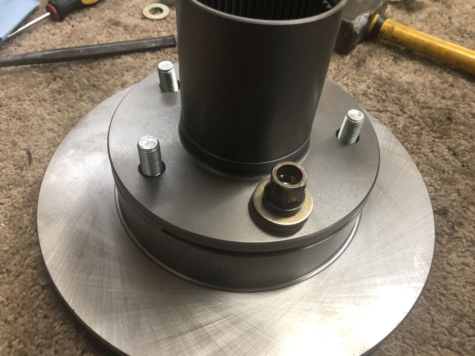 Brake rotor and hub assembly with wheel studs and splined shaft on carpet, tools nearby