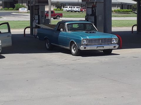 1994 Ford Bronco - A blue pickup truck is parked at a gas pump, with a silver car to its left.