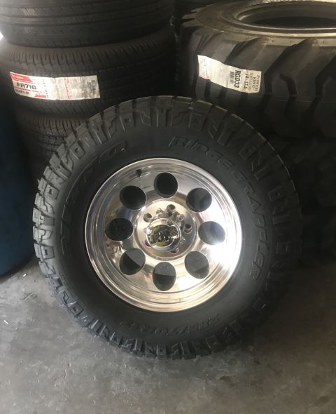 1995 Ford Bronco - A single chrome wheel and tire is shown in front of a stack of other tires.