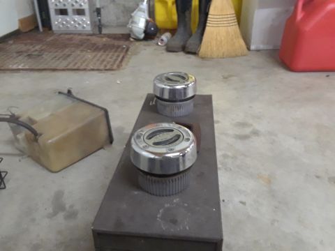 1994 Ford Bronco - Two hubcaps are displayed on a metal plate, with a plastic tank nearby.