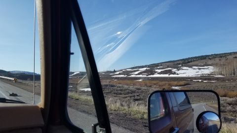 1985 Ford Bronco - Driving through a landscape with patches of snow on the hills under a clear blue sky.