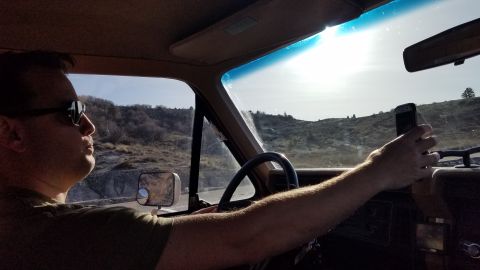 1985 Ford Bronco - Driver captures a selfie while navigating a scenic route in a 1985 Ford Bronco.