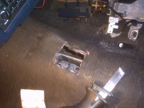 1991 Ford LTD Crown Victoria - A hole has been cut into the car's floor, exposing wiring and mechanical components underneath.
