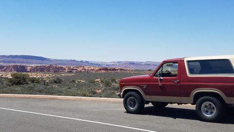 1985 Ford Bronco - A 1985 Ford Bronco is parked on the side of the road with a scenic desert view.