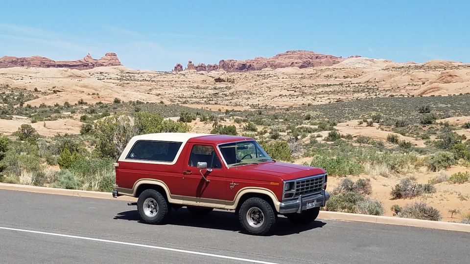 1985 Ford Bronco parked on roadside with desert rock formations in background