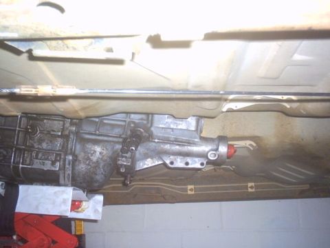 1991 Ford LTD Crown Victoria - The underside of a vehicle's transmission is visible, with a red jack supporting it.