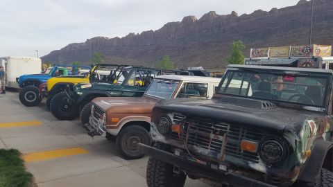 1985 Ford Bronco - Multiple Ford Broncos are lined up, with a desert mountain range in the background.