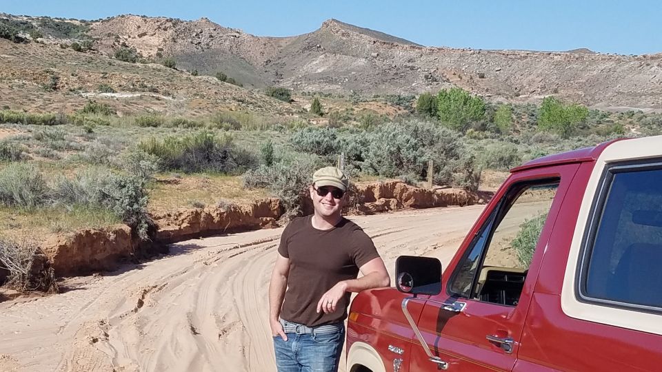 Red 1980s Ford Bronco parked on a dirt road in a desert landscape
