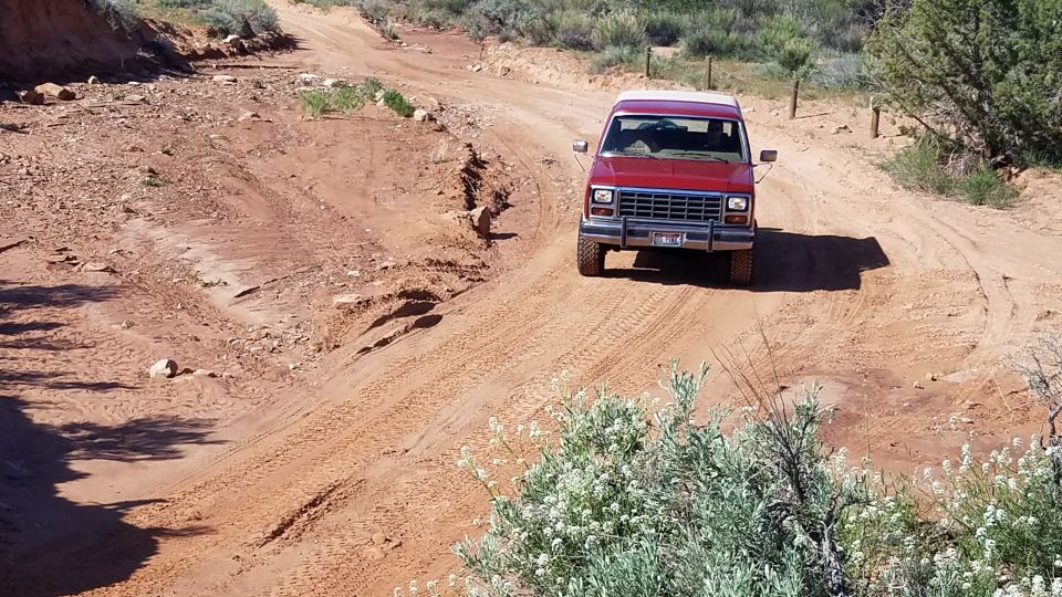 red SUV driving on a dirt road in a desert landscape