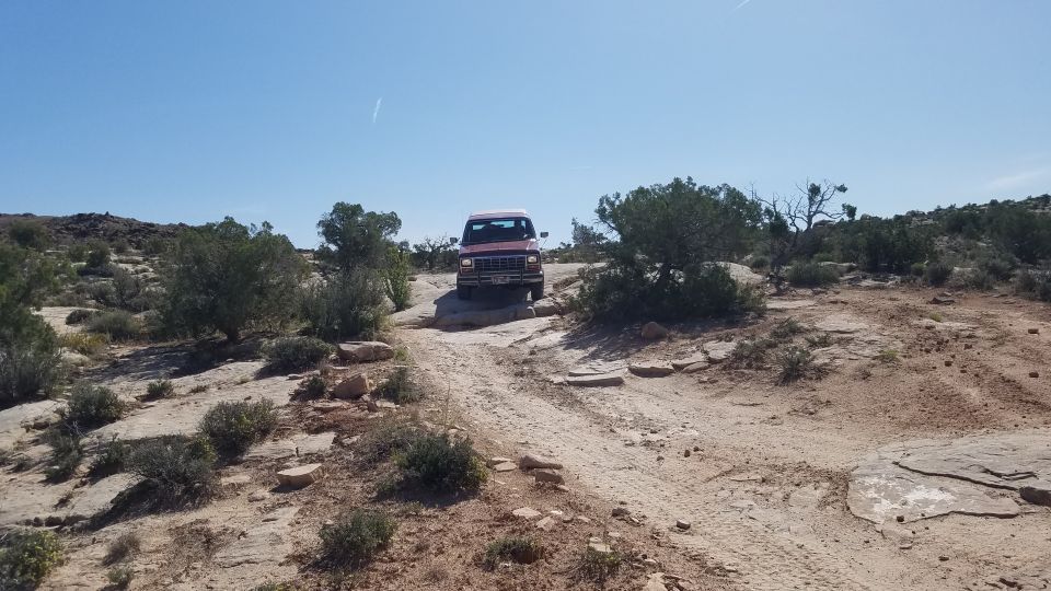 Red SUV on a rocky trail, front view, clear sky