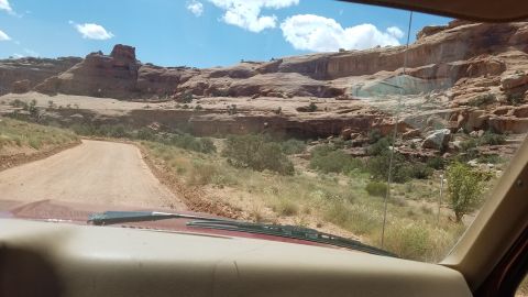 1985 Ford Bronco - Driving on a dirt road through a desert canyon with red rock formations.