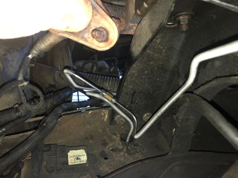 1995 Ford Bronco - Underneath view of a vehicle's engine bay showing a metal brake line routed along the frame and connected to a sensor with a label reading…