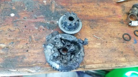 1985 Ford Bronco - Two heavily greased metal gears are on a weathered wooden surface. The gears appear to be damaged.