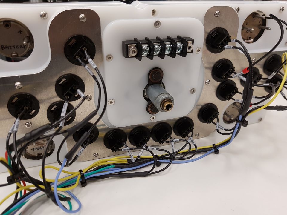 Custom dashboard wiring harness with multiple gauges and a central ignition switch, showing electrical connections and labels