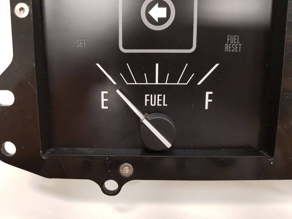 Close-up of a black fuel gauge with E and F markings and a needle pointing to low fuel.