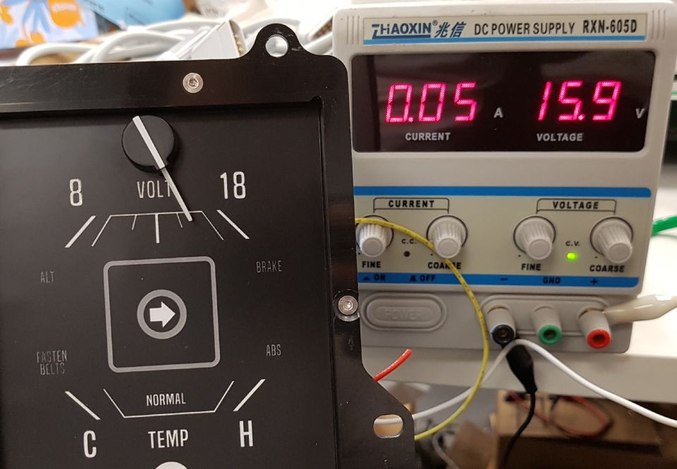 Vintage analog gauge next to a digital DC power supply showing 0.05A current and 15.9V voltage.
