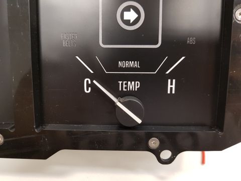 1978 Ford Bronco - A close-up view of a black automotive gauge cluster with a temperature gauge in the center. The gauge shows the needle pointing towards the…