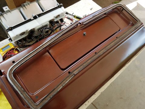 1978 Ford Bronco - A metallic brown dashboard panel with a recessed compartment is shown, with a cluster of gauges and wiring visible in the background. Tools…