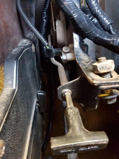 1978 Ford Bronco - This is a close-up view of the brake release lever and associated wiring and linkage under the dashboard of a vehicle. The lever has the te…