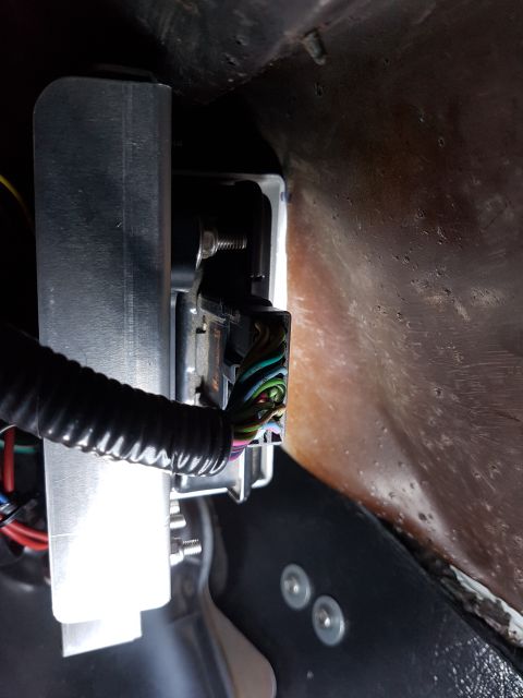 1978 Ford Bronco - A close-up view shows a black electrical connector plugged into a silver metal housing, with a bundle of colorful wires emerging from the c…