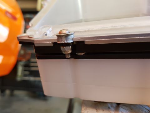 1978 Ford Bronco - A close-up shot shows a bolt and nut securing a clear plastic lid to a white plastic housing, with a black gasket visible between the two c…