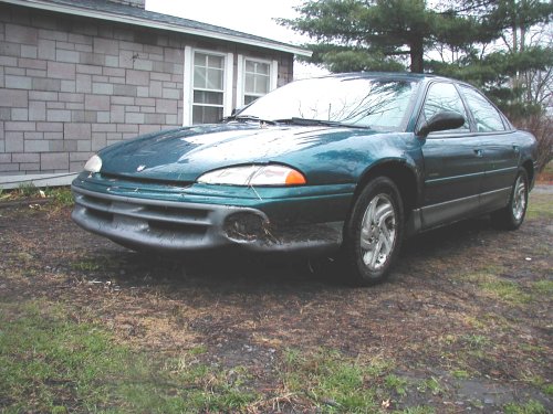 Green sedan parked outside a brick house. Front bumper is damaged