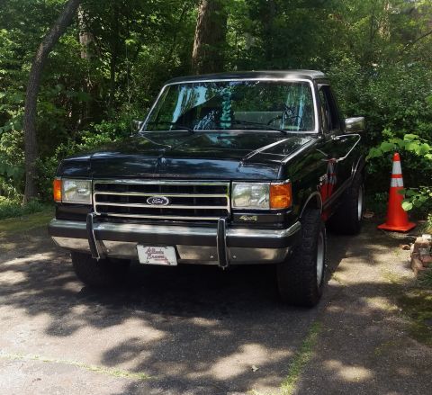1988 Ford Bronco - Front view of a black 1987 Ford F-150 pickup truck with a red stripe on the side.