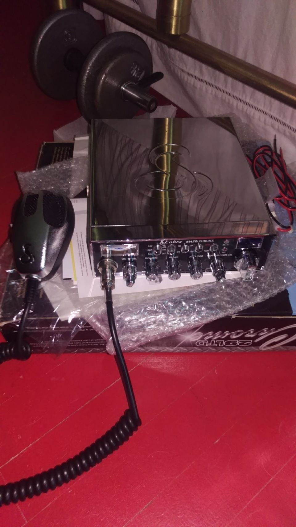 Chrome CB radio with black microphone and coiled cord on a red surface