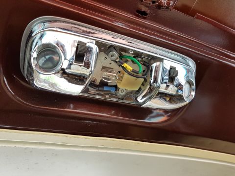 1978 Ford Bronco - Interior dome light assembly showing wiring and bulb, mounted in a dark red car body panel.