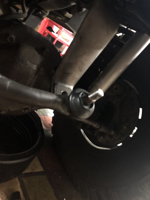 1995 Ford Bronco - Close-up of a vehicle's steering linkage, focusing on a ball joint assembly.