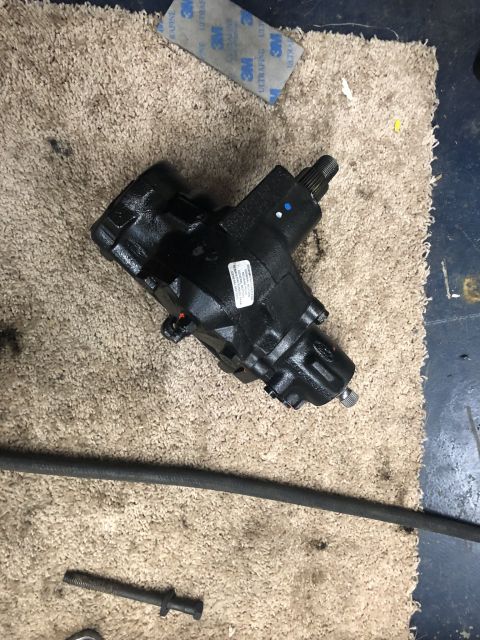 1995 Ford Bronco - A black steering gear box is shown on a tan mat, with a black hose and some tools nearby.