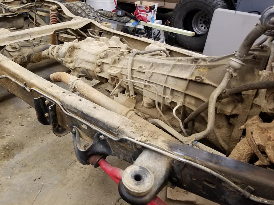 Dirty truck frame, transmission and front axle exposed during chassis work in a garage
