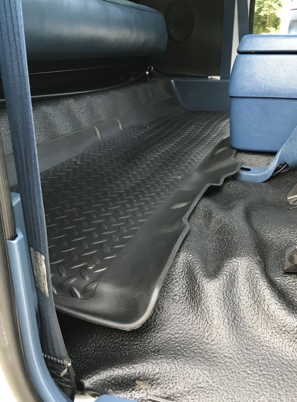 Blue seat and black diamond-plate floor mat in a vehicle interior