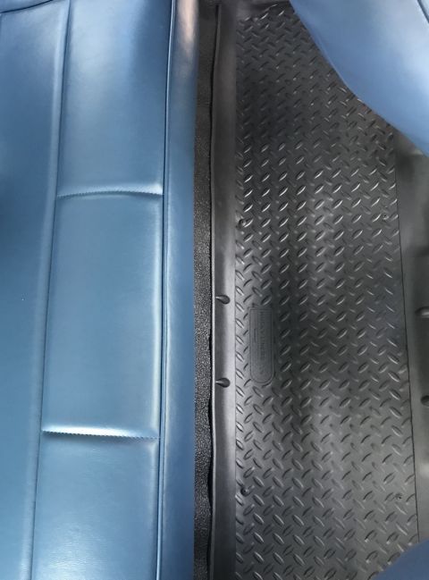 1995 Ford Bronco - Close-up view of the interior of a vehicle, showing a blue seat and a black floor mat.