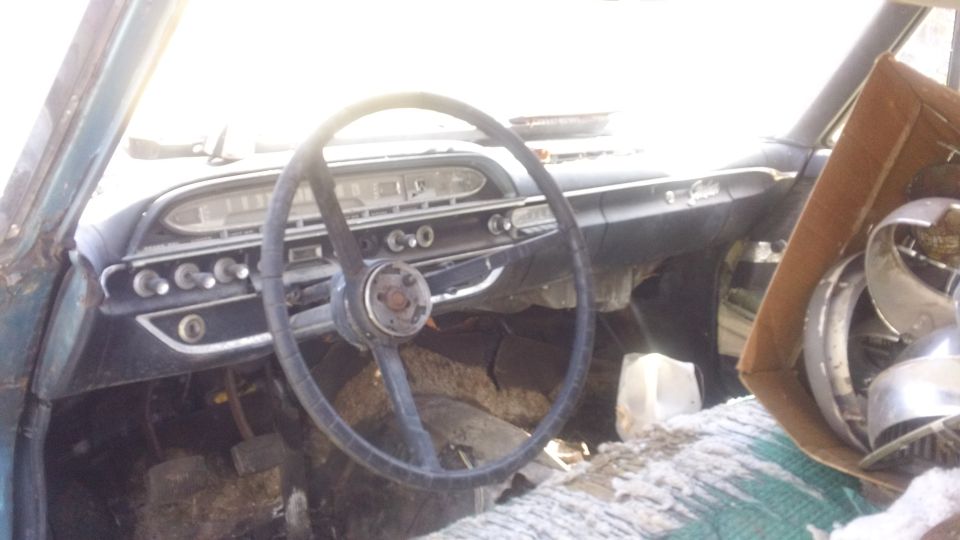 1961 Ford Starliner interior showing dashboard, steering wheel, and parts in a box