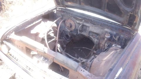 1961 Ford Starliner - The engine bay of a 1961 Ford Starliner appears empty and rusted.