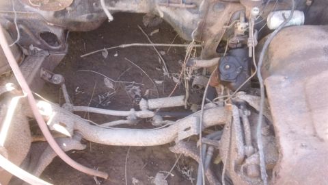 1961 Ford Starliner - Close-up of a heavily rusted car chassis, showing steering components and suspension parts.