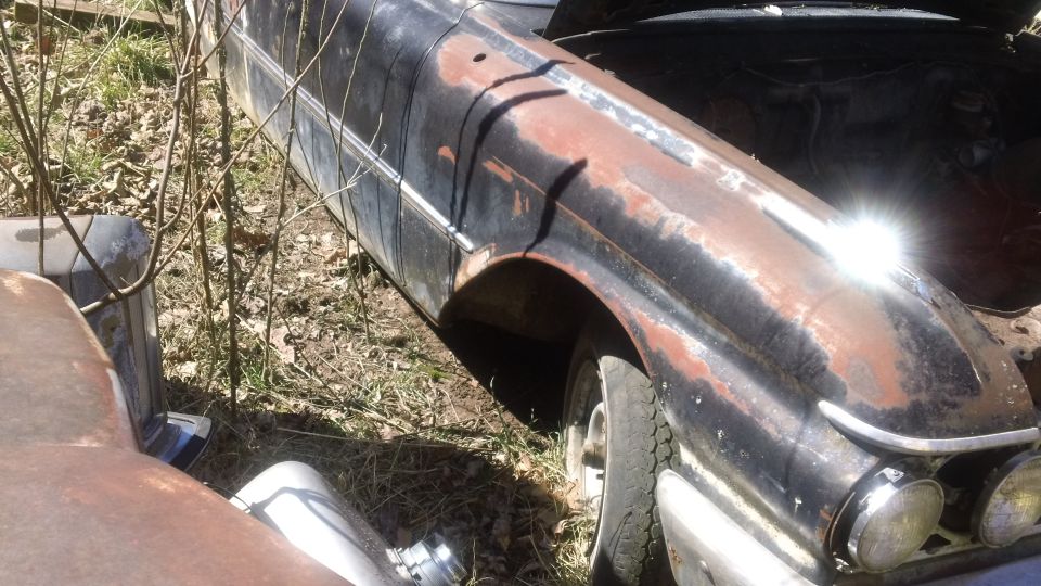 rusty car with hood up, parked outside