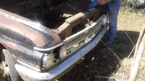 1961 Ford Starliner - A heavily rusted car's front end is visible, with its hood open and a person standing next to it.