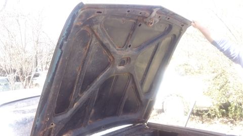 1961 Ford Starliner - The underside of a car hood reveals its internal structure and signs of wear and tear.
