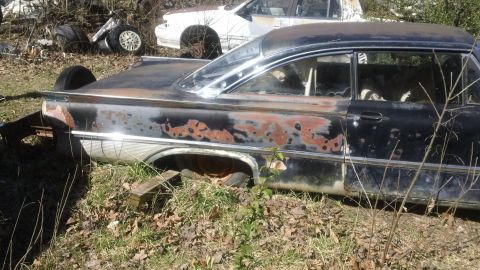 1961 Ford Starliner - This weathered car sits in a junkyard, showing significant rust and damage, with another vehicle visible in the background.