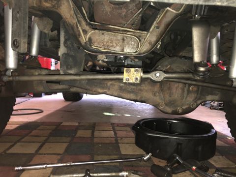 1995 Ford Bronco - Undercarriage view shows steering linkage and differential, with tools and a drain pan present.