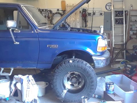 1996 Ford F-350 - A blue 1996 Ford F-350 truck is shown in a garage with its hood up and large tires.